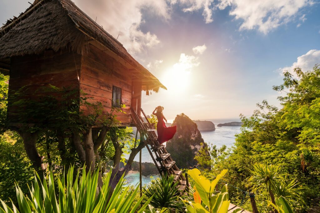 Action im Urlaub: Junge Frau Reisende genießen und suchen schönen Sonnenaufgang am Baumhaus